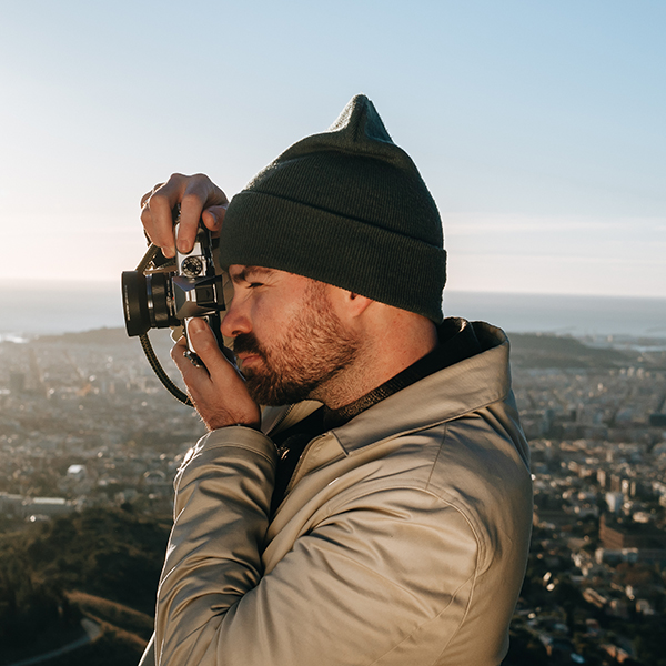 This is a photo of a photographer holding the OM SYSTEM OM-3 camera with the M.ZUIKO DIGITAL 17mm F1.8 II lens attached to the camera body.