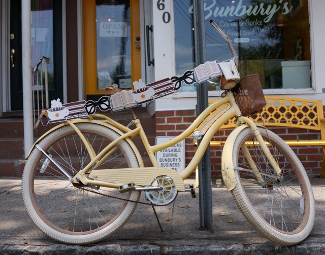 A yellow bicycle leans againast a pole