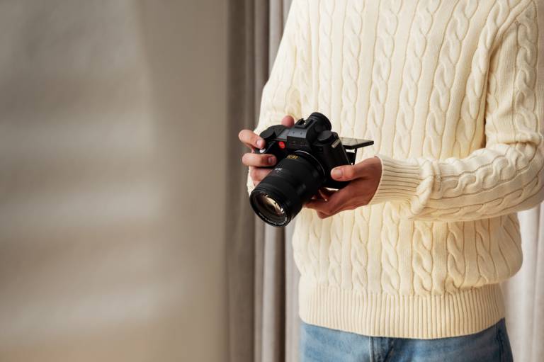 A person holding a Lieca camera