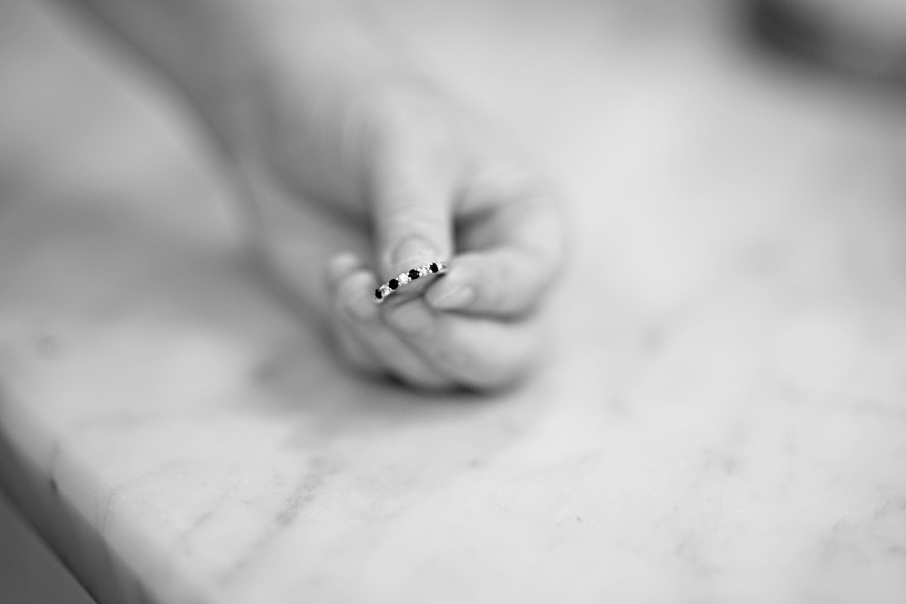 A hand holds a wedding ring. 