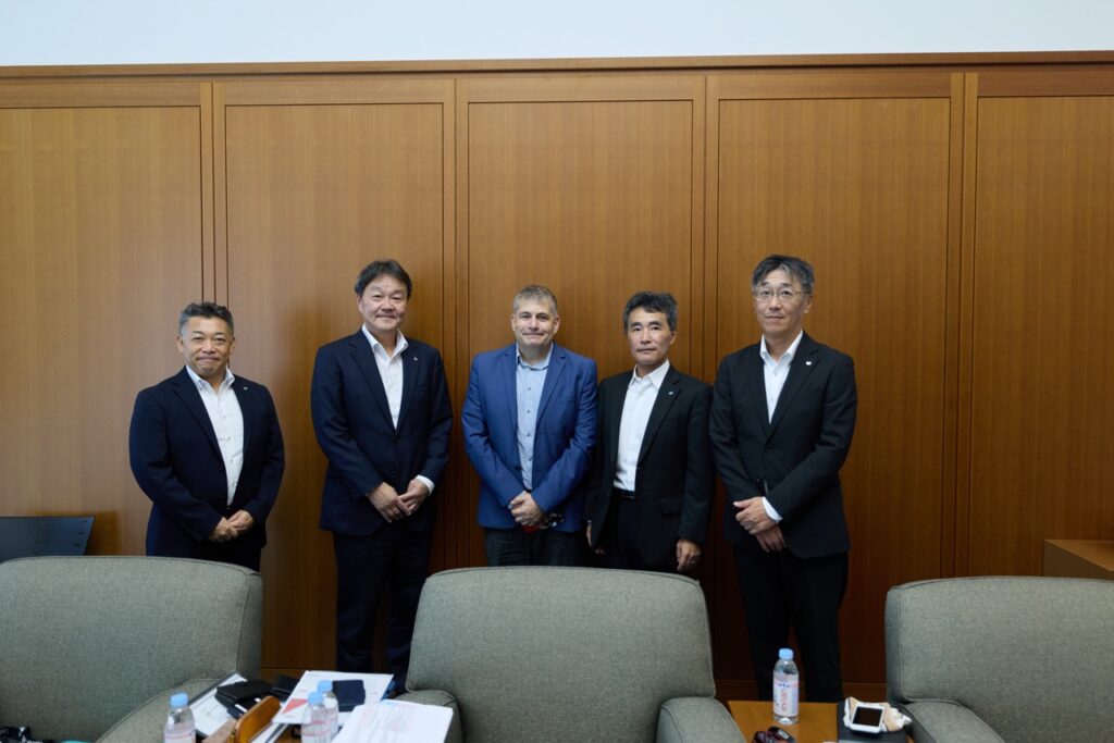 Four executives and the author stand in a conference room facing the camera.