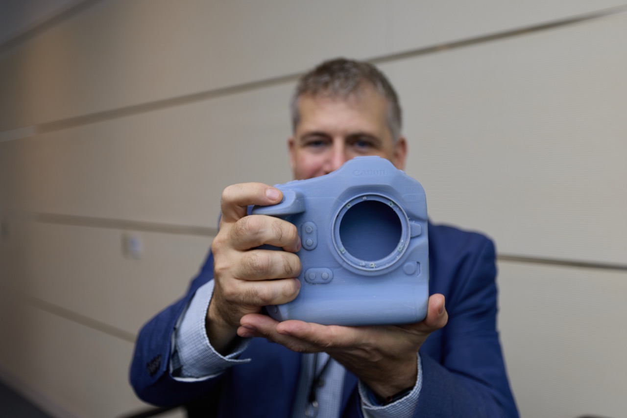 The author holds a Canon R1 3D Printed prototype. 