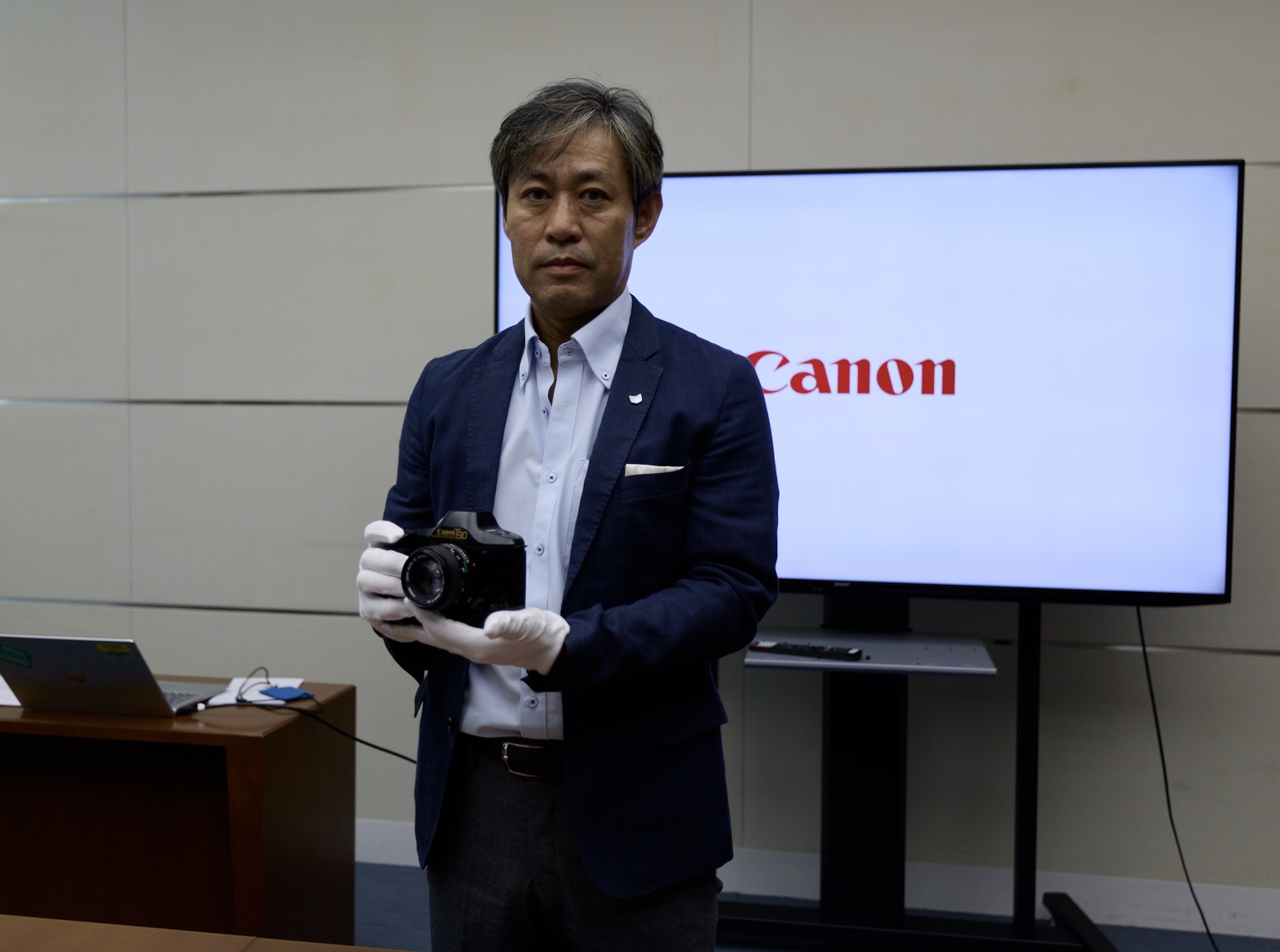 An excutive holds a Canon T-90 in his glvoed hands. 