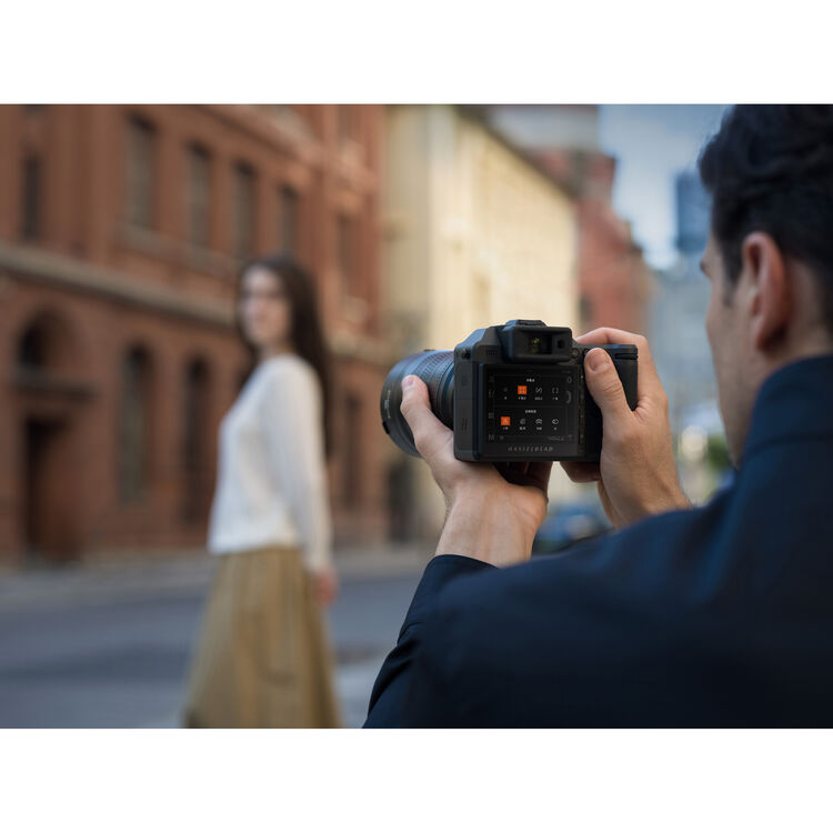 Hasselblad X2D II 100C being used in a street by a photogarpher and a female model