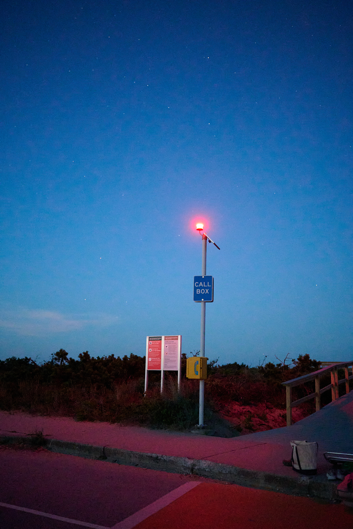 A callbox at a beach lit only wiht the light of the callbox.