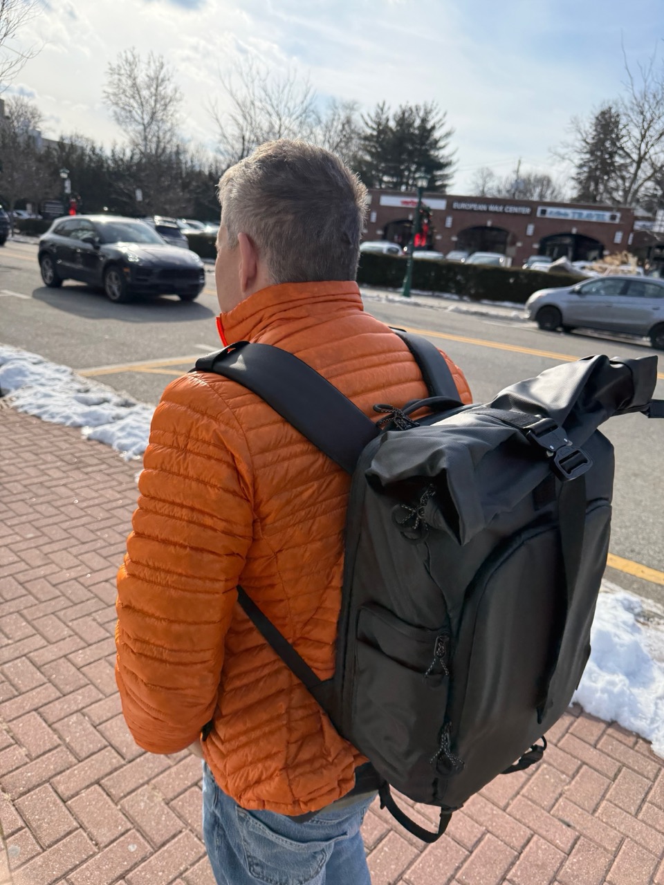 A man in an orange jacked with a backpack on. 