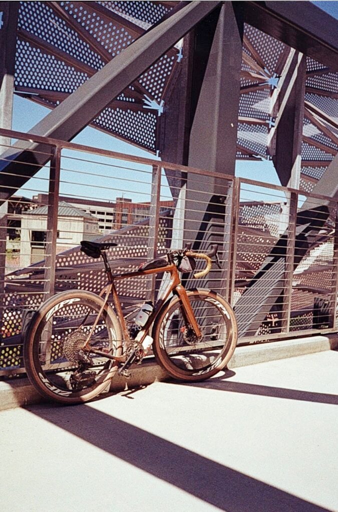 A bicycle leaning against the fence on a pedestrian bridge.