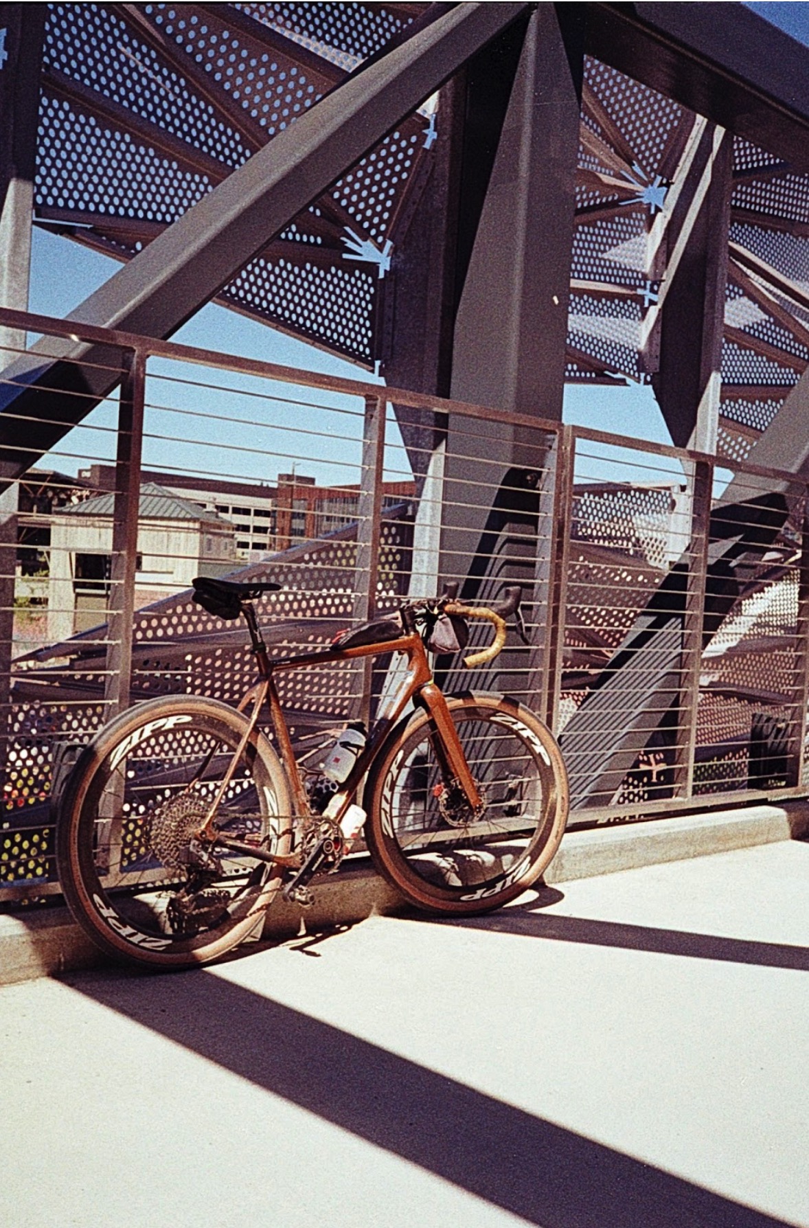 A bicycle leaning against the fence on a pedestrian bridge. 