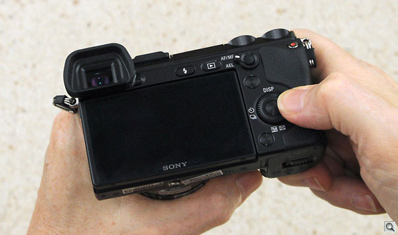 The rear dial really requires you hold the camera in front of you, but the two-handed